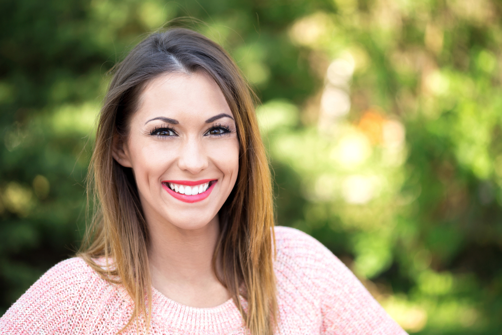 Beautiful young girl smiling at the camera in the park outside